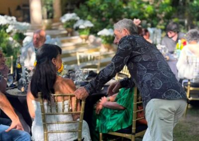 Guests mingling at elegant outdoor garden wedding reception with gold chairs and floral centerpieces.