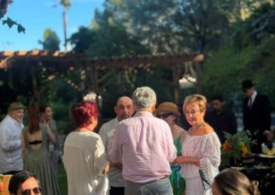 Guests mingling at an outdoor garden wedding reception with sunflower centerpieces and wooden pergola in the background.