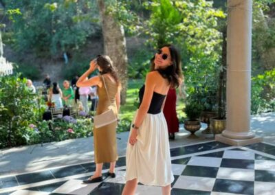 Woman in black and white dress and sunglasses posing on checkered marble patio at outdoor garden event.
