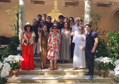 Group of well-dressed people posing on outdoor stone steps surrounded by white orchids and lush greenery