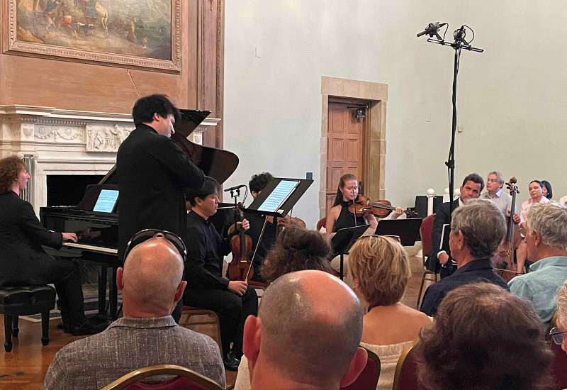Greystone Mansion Classical chamber music concert with pianist, string musicians performing for seated audience in elegant historic hall.
