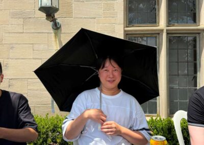 Person holding black umbrella for shade while dining outdoors with pizza and salad at Italian restaurant patio table.